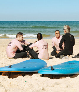 4 personnes discutent sur une plage de Biscarrosse avec un moniteur de surf et plusieurs planches.