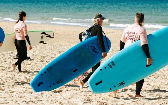2 surfeurs avec une planche à la main sur une plage de Biscarrosse.